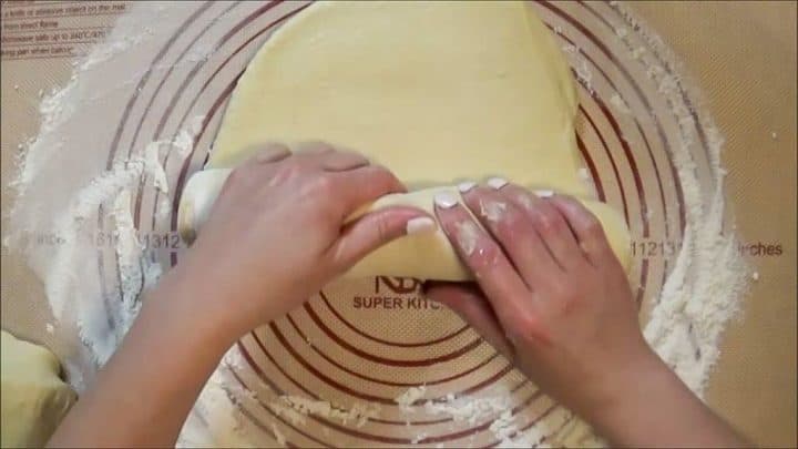 Rolling up butter bread dough loaf to shape into a bread loaf before final rise.