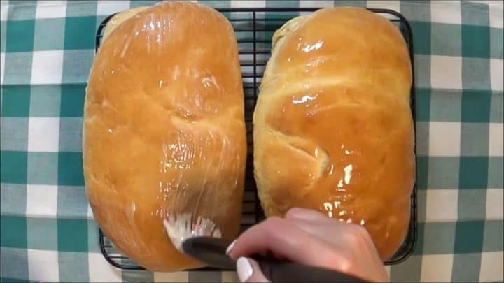 Brushing the tops of baked butter bread loaves with softened salted butter right after they came out of the oven.