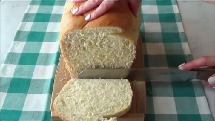 Slicing homemade butter bread with a long carving knife.