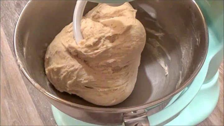 Mixing butter bread dough in an electric stand mixer with a dough hook attachment.