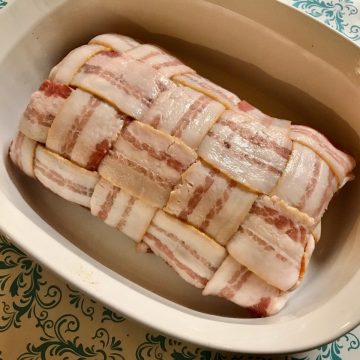 Grilled Pork Loin Wrapped in Bacon in a white cooking dish.
