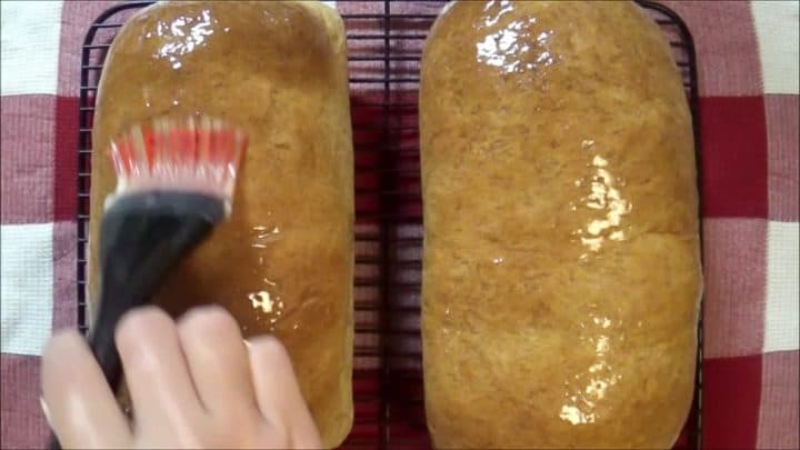 Brushing butter on baked honey wheat bread