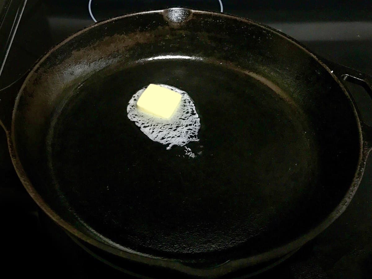 Butter melting in a black cast iron skillet.
