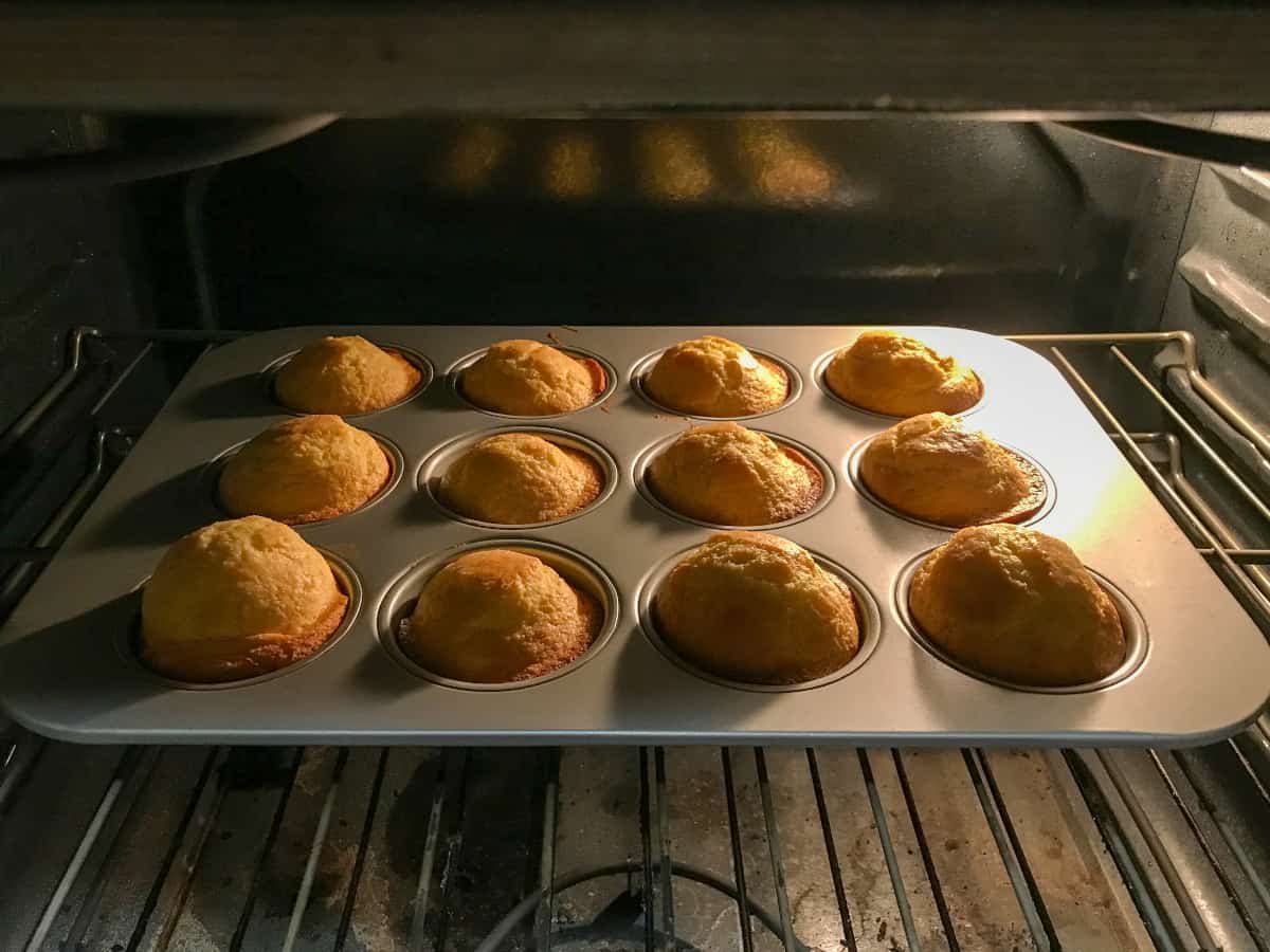 Cornbread muffins cooking in an oven.