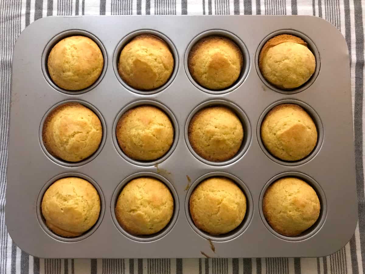 Baked cornbread muffins cooling on a towel.