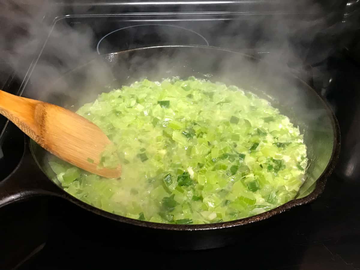 Chopped celery and onions cooking in a skillet.