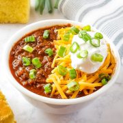 Slow Cooker Venison Chili (deer chili) in a white bowl with cornbread and green onions.
