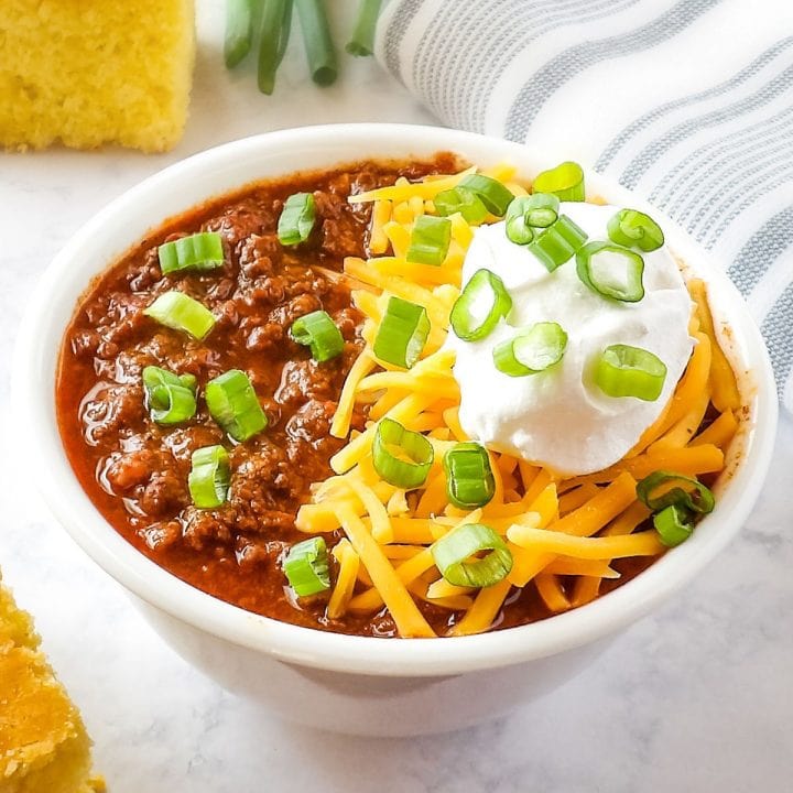 Slow-Cooker Deer (Venison) Chili in a white bowl with cornbread and green onions.