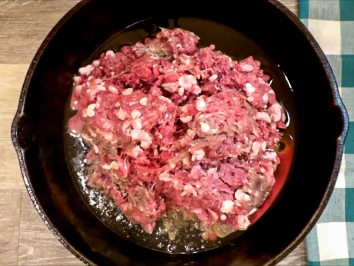 Raw ground venison in a hot cast iron skillet.