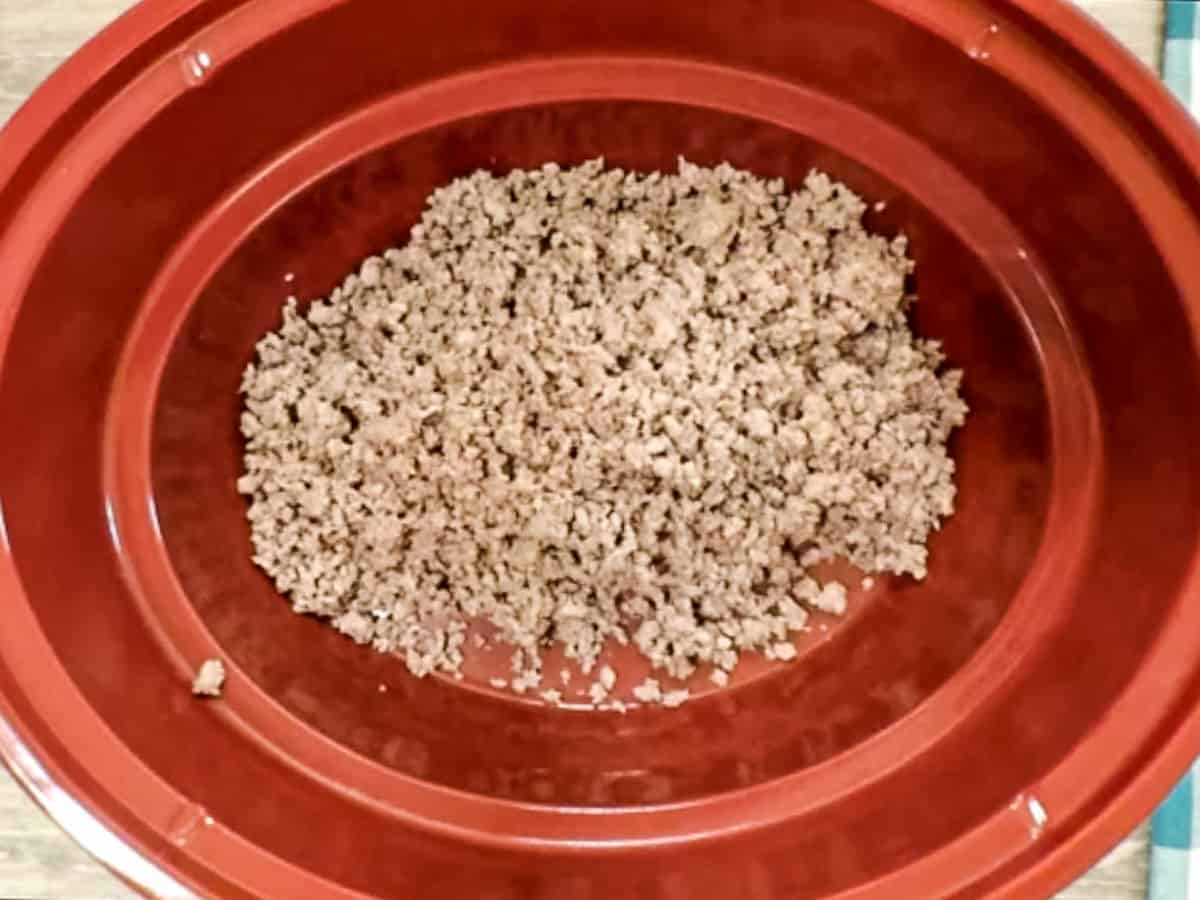 Browned ground venison meat in a red crockpot.