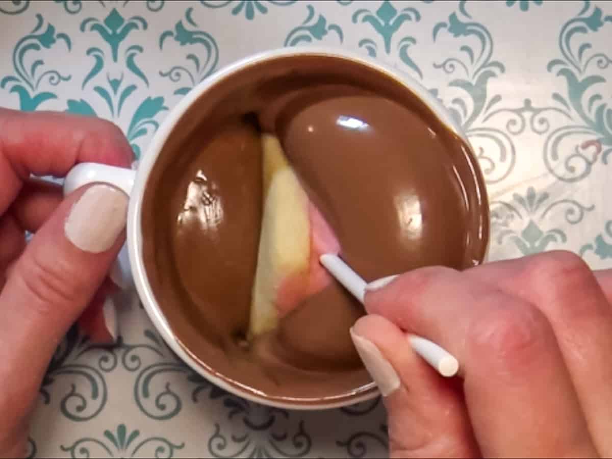 Dipping a sandwich cookie pop in chocolate.