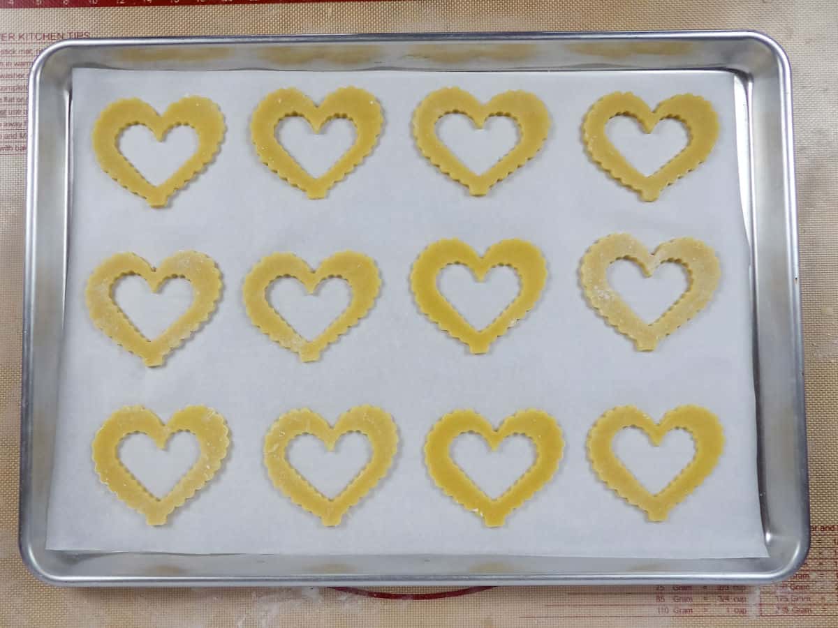 Scalloped heart shaped cookie cutouts laying on a baking sheet.