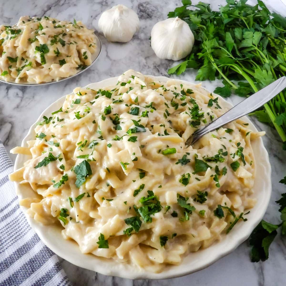 Cooked chicken fettuccine alfredo on a white plate garnished with fresh parsley.
