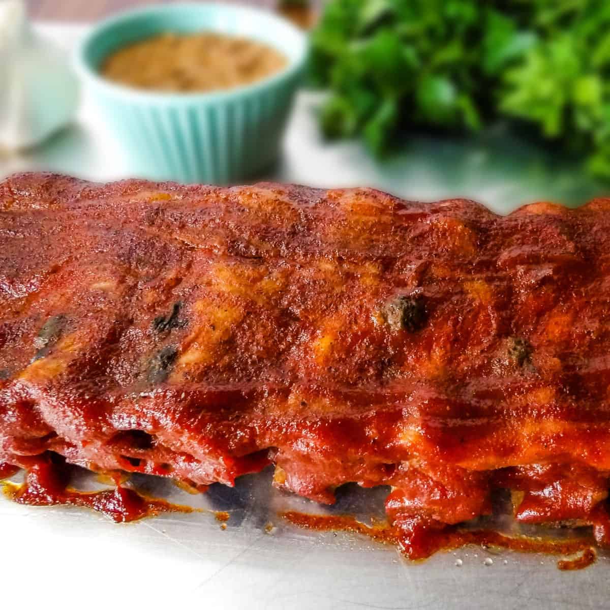 A rack of baby back pork ribs that have been cooked in the Instant Pot laying on a baking sheet.