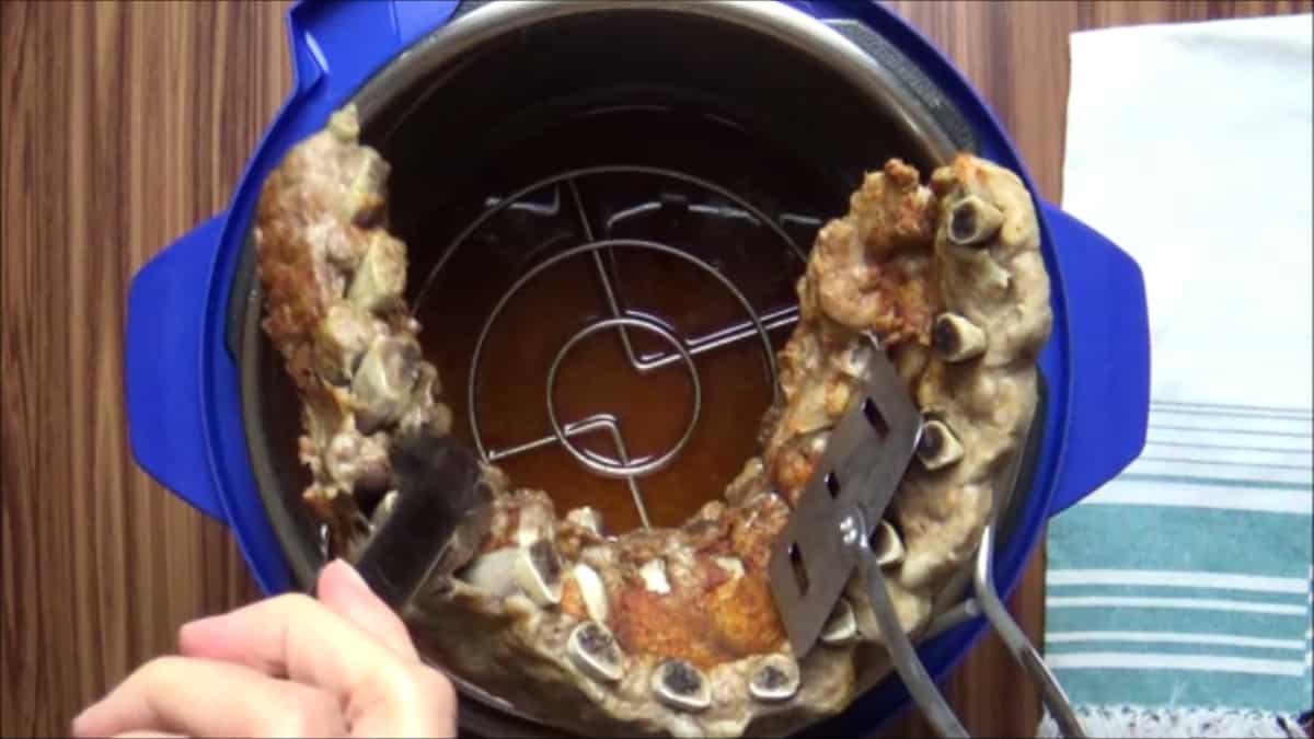Removing a rack of cooked baby back pork ribs from the Instant Pot.