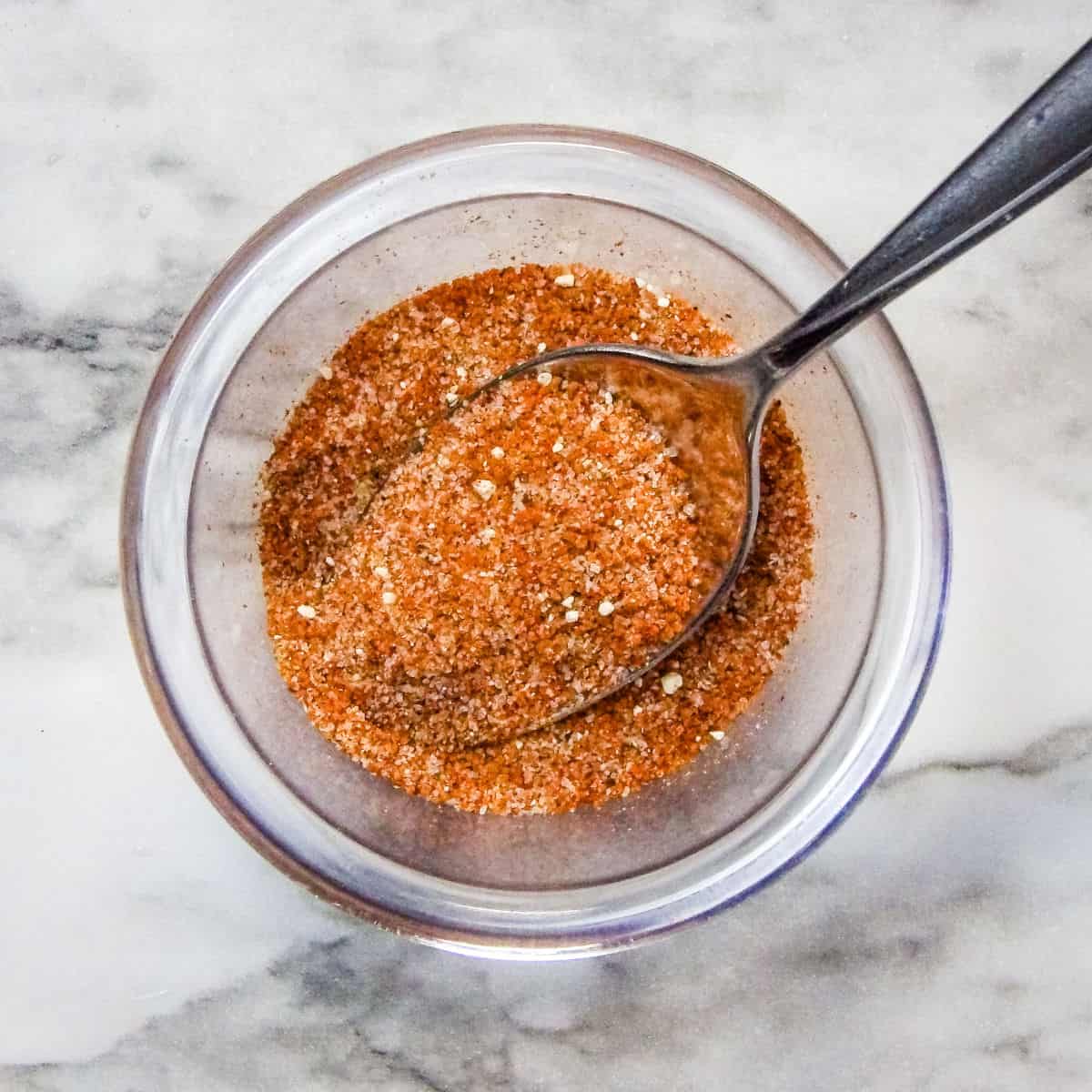 Sweet Dry Rub for Pork Ribs in a clear bowl with a silver spoon.