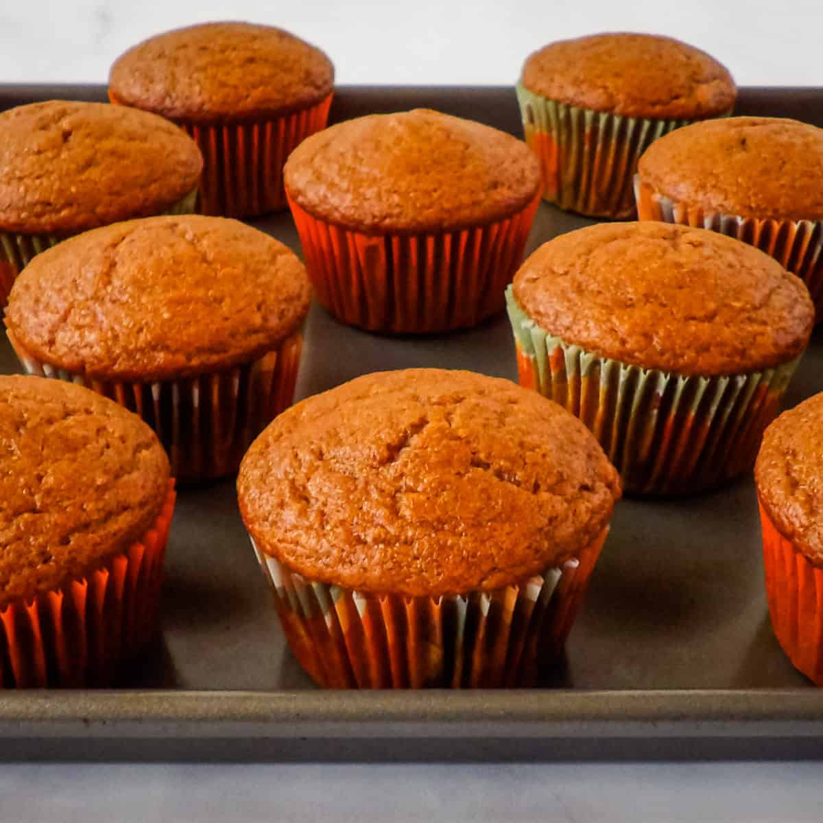 Cooked pumpkin cupcakes cooling on a baking sheet.