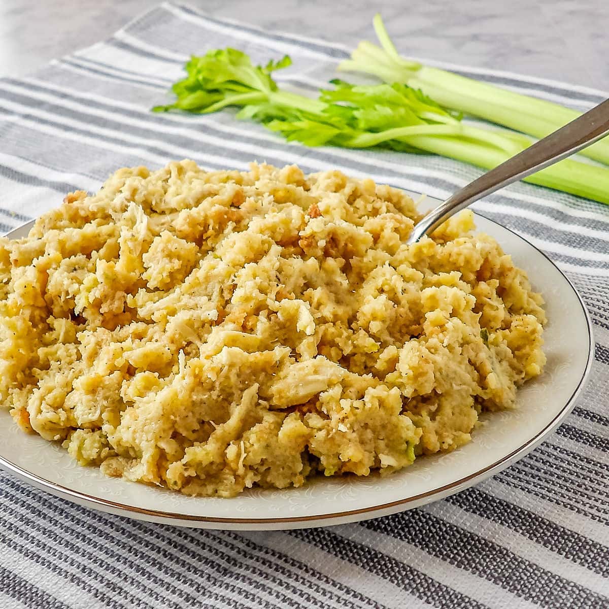 Cooked Chicken and Dressing Casserole laying on a white marble table with a celery stalk behind it.