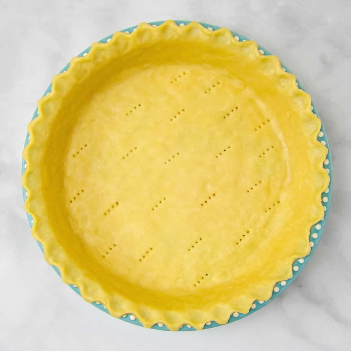 Homemade pie crust in a blue pie dish.