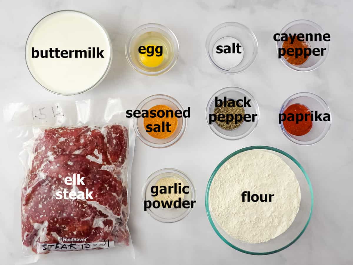 Ingredients for chicken fried elk steak (buttermilk, elk steak, egg, salt, cayenne pepper, seasoned salt, black pepper, paprika, garlic powder, and flour).