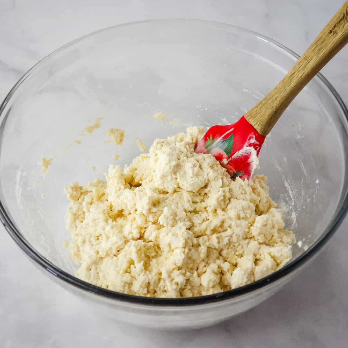 Folding buttermilk into self-rising flour in a glass bowl.