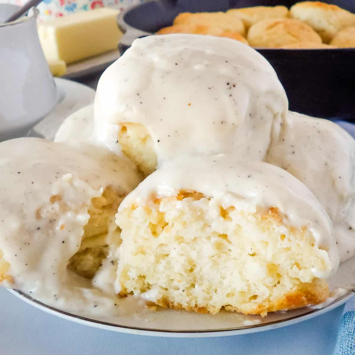 Homemade buttermilk biscuits topped with white cream gravy on a white plate.