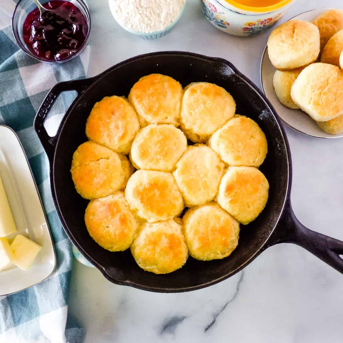 Baked homemade biscuits in a black cast-iron skillet on a white marble countertop.