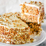 A slice of homemade carrot cake being lifted from the cake with a silver cake server.
