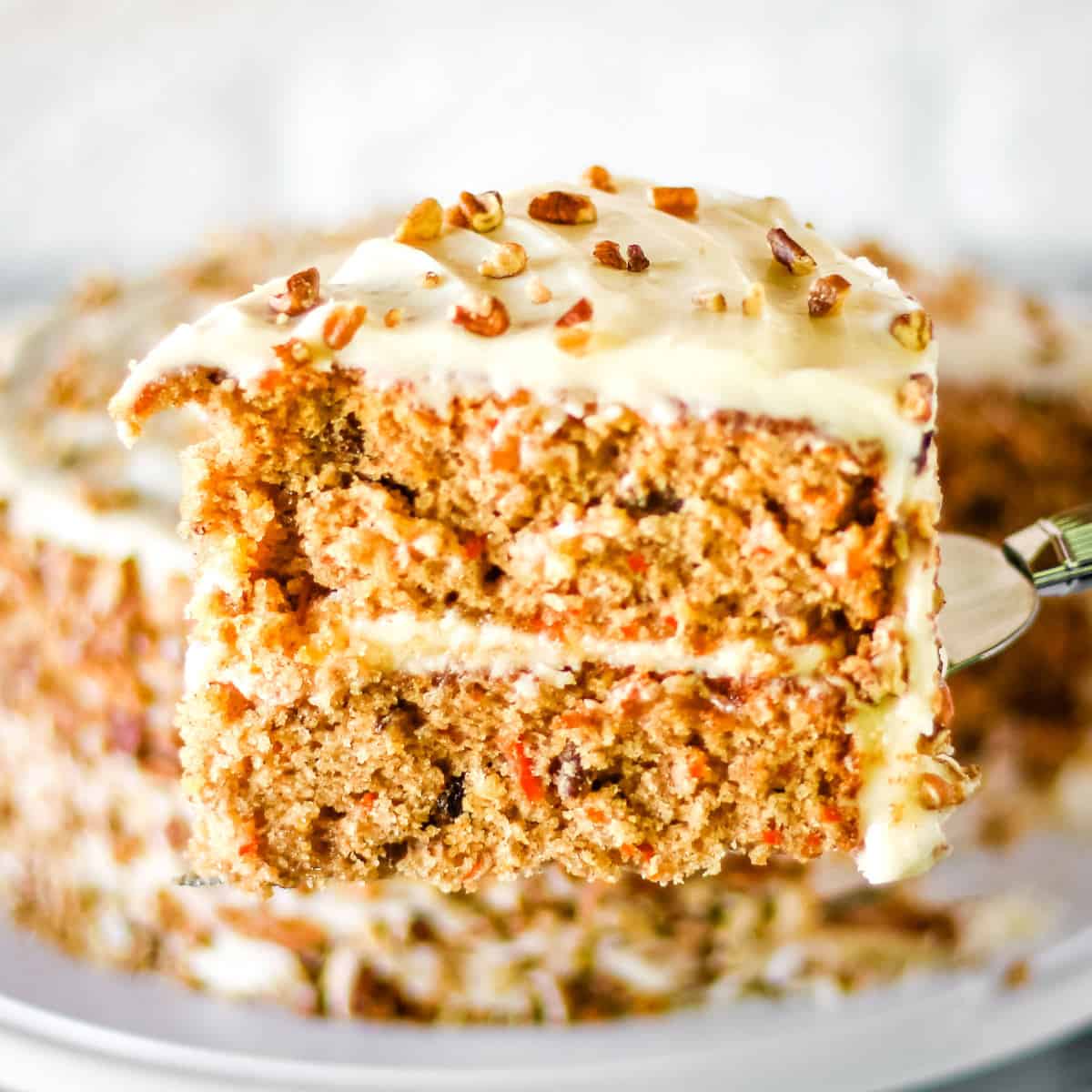 Close up of a slice of homemade carrot cake on a silver cake server.