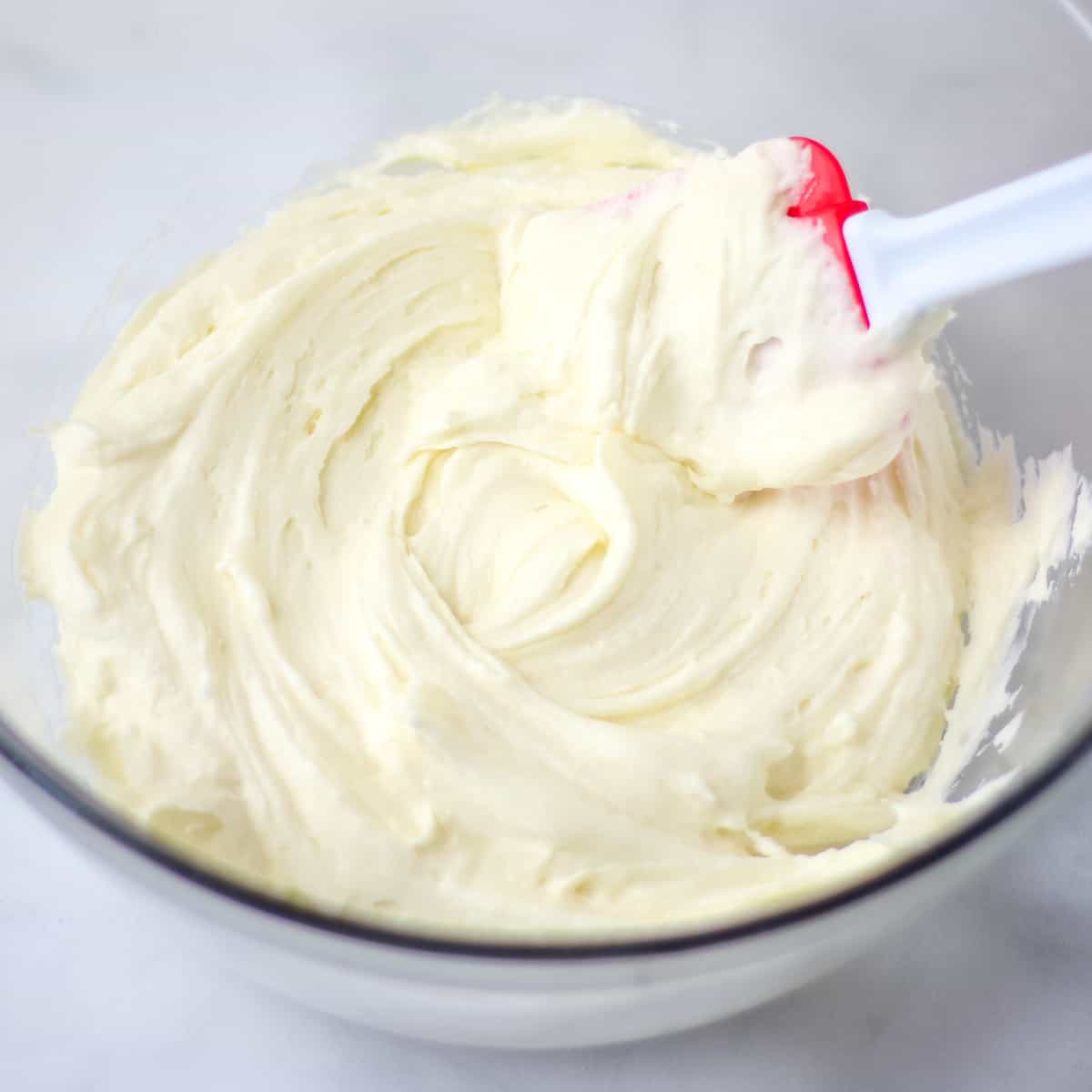 Homemade cream cheese frosting in a glass bowl.