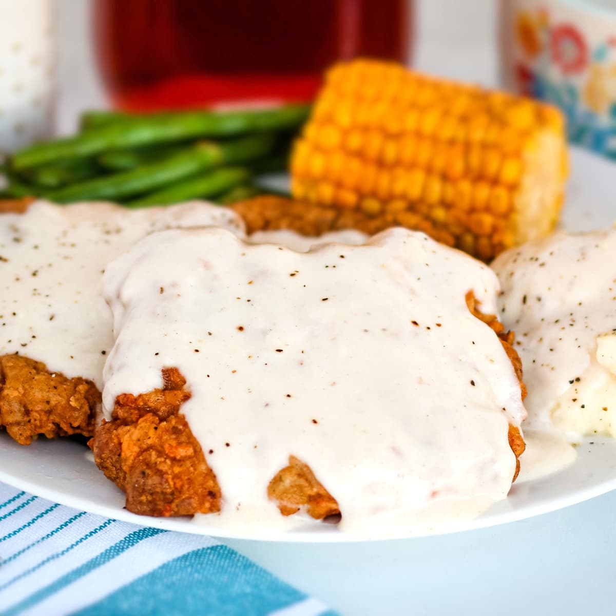 Pan fried venison steak topped with white cream gravy on a white plate.