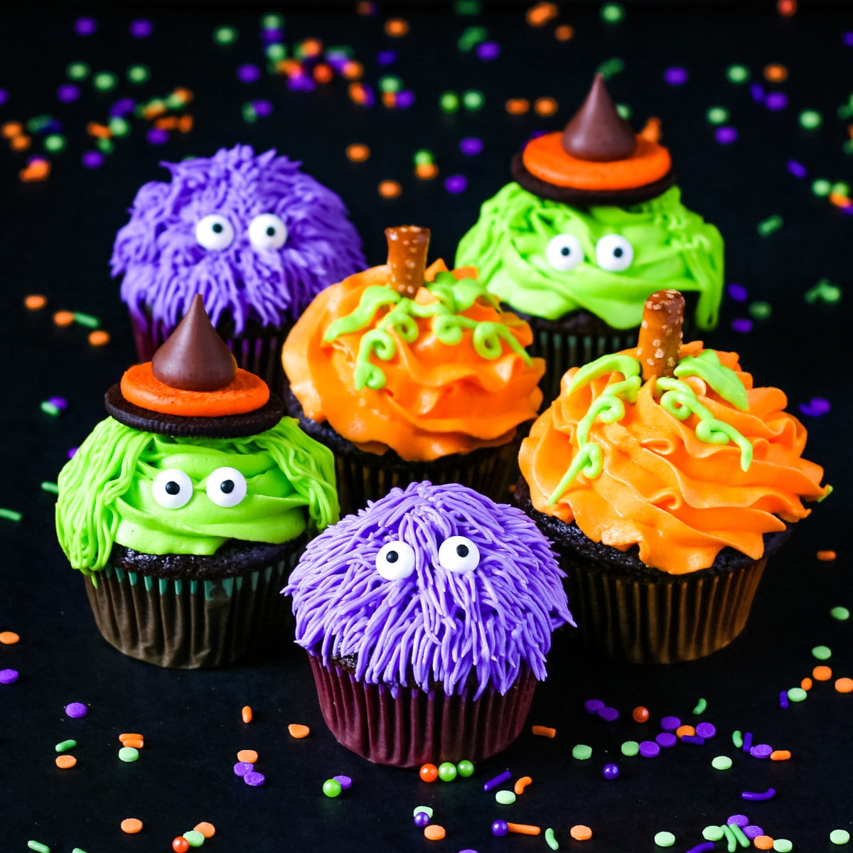 Cute Halloween cupcakes decorated as purple monsters, green witches, and orange pumpkins.
