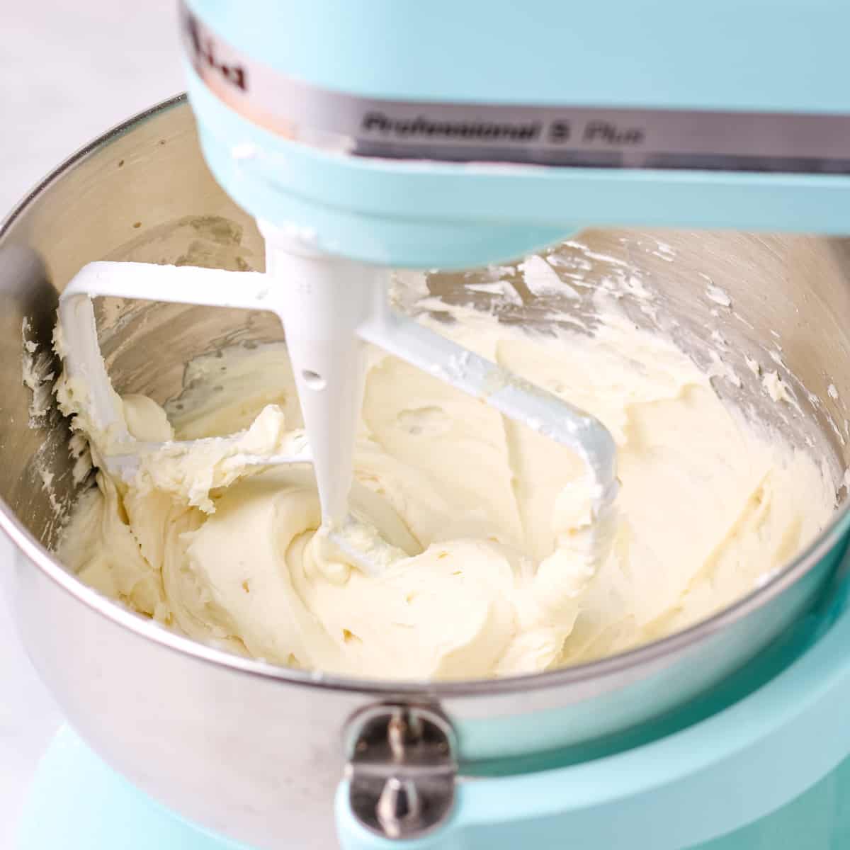 Mixing homemade buttercream frosting in a blue electric stand mixer.