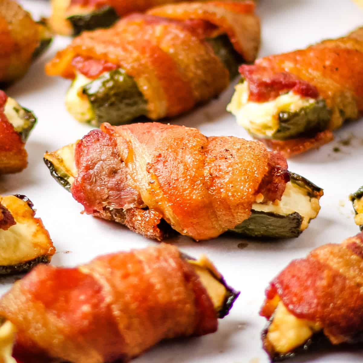 Smoked bacon wrapped venison jalapeno poppers on a white countertop.