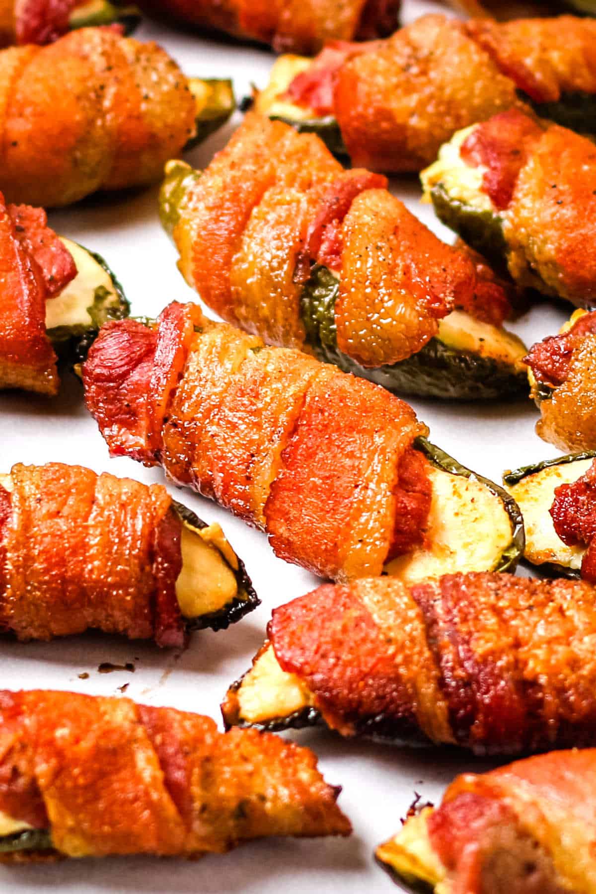 Smoked venison jalapeno poppers on a white sheet of parchment paper.
