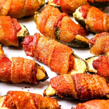 Smoked venison jalapeno poppers on a white sheet of parchment paper.