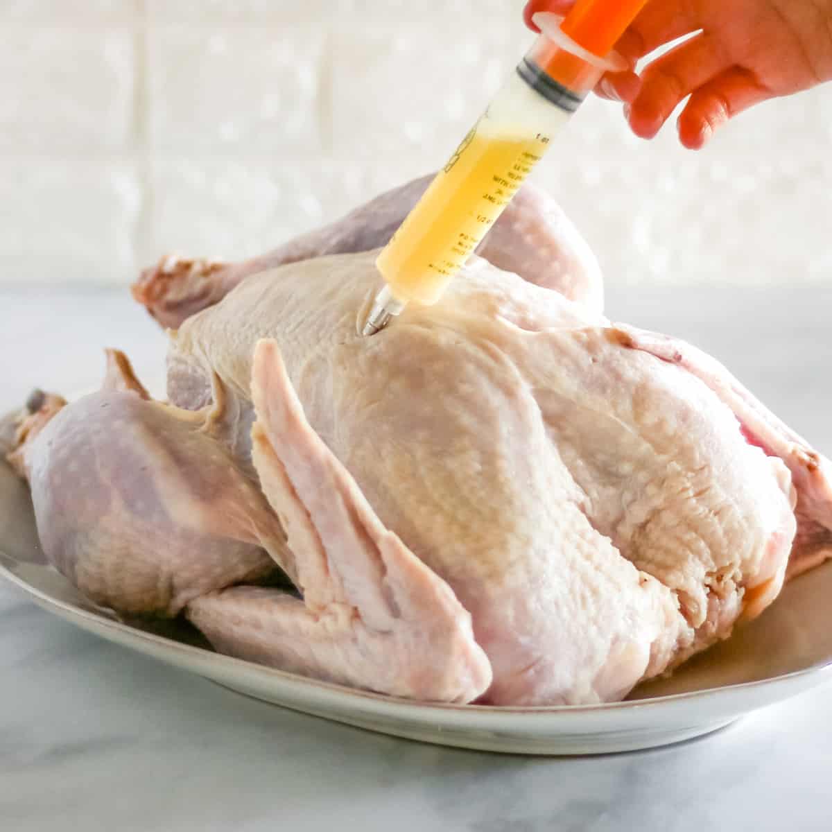 Injecting the turkey with the butter/broth mixture.
