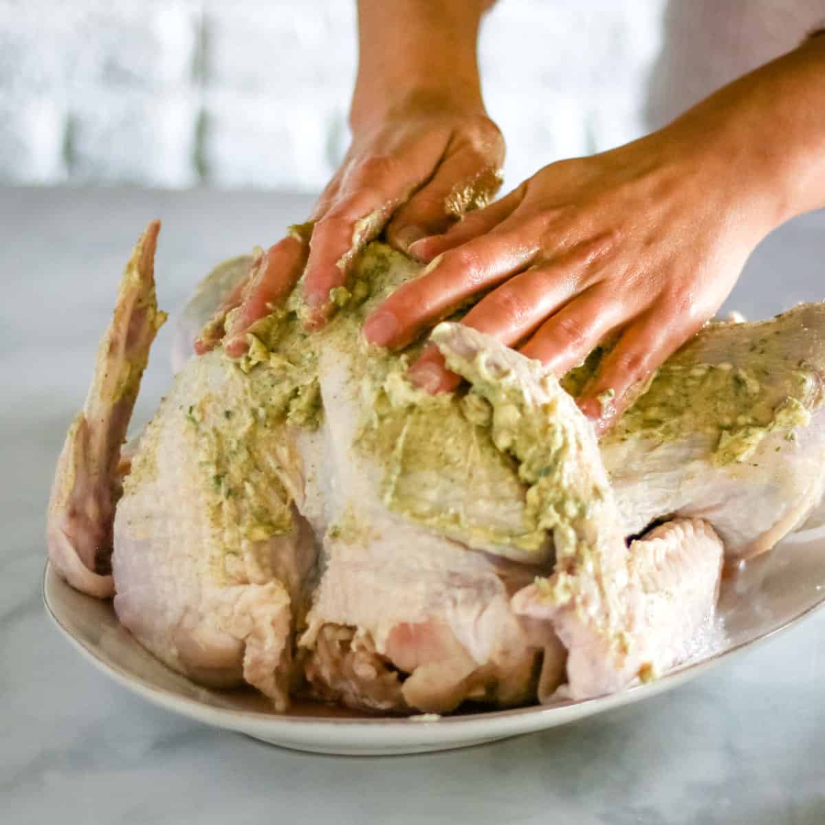 Rubbing the garlic herb butter onto the turkey skin.
