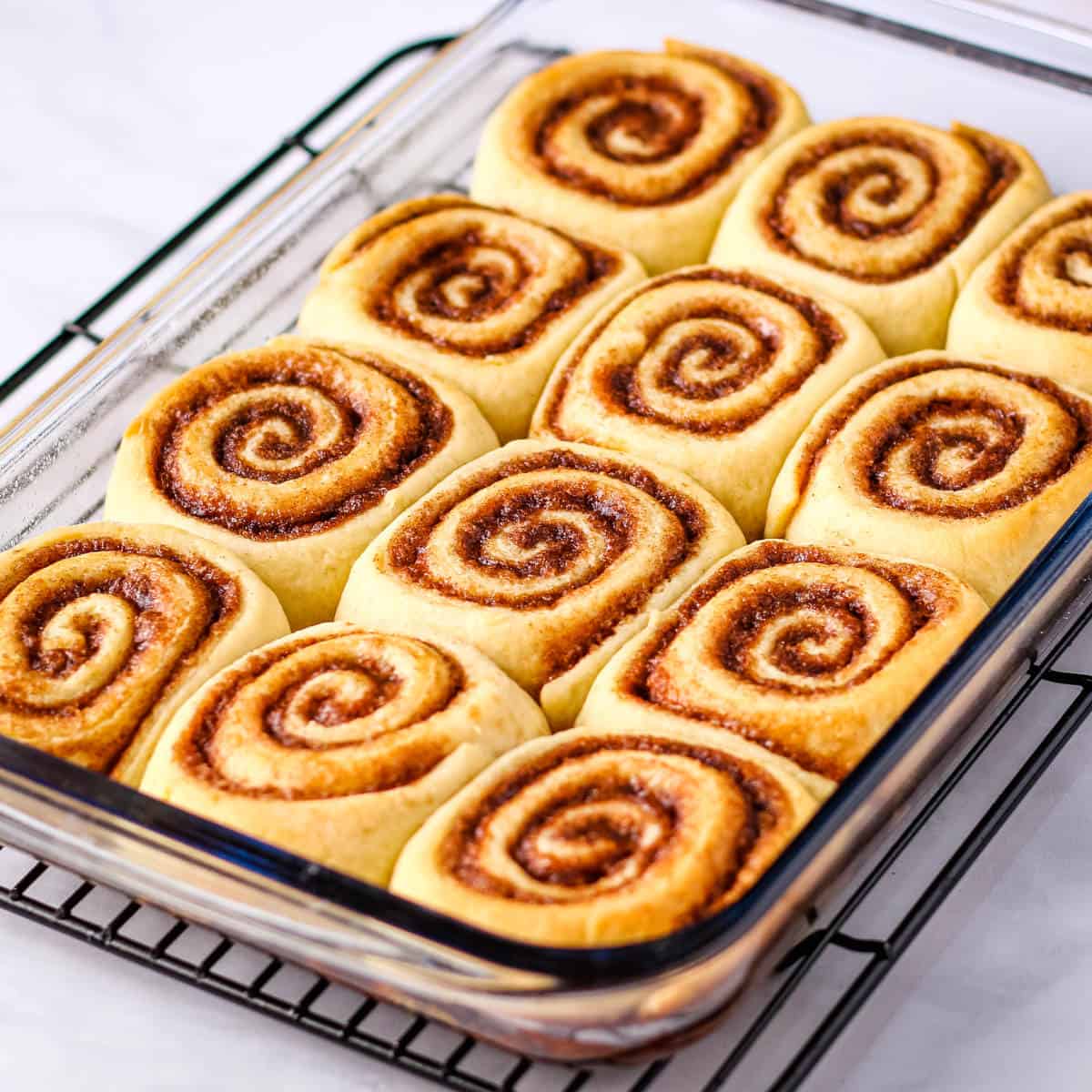 Baked cinnamon rolls in a clear glass baking dish.