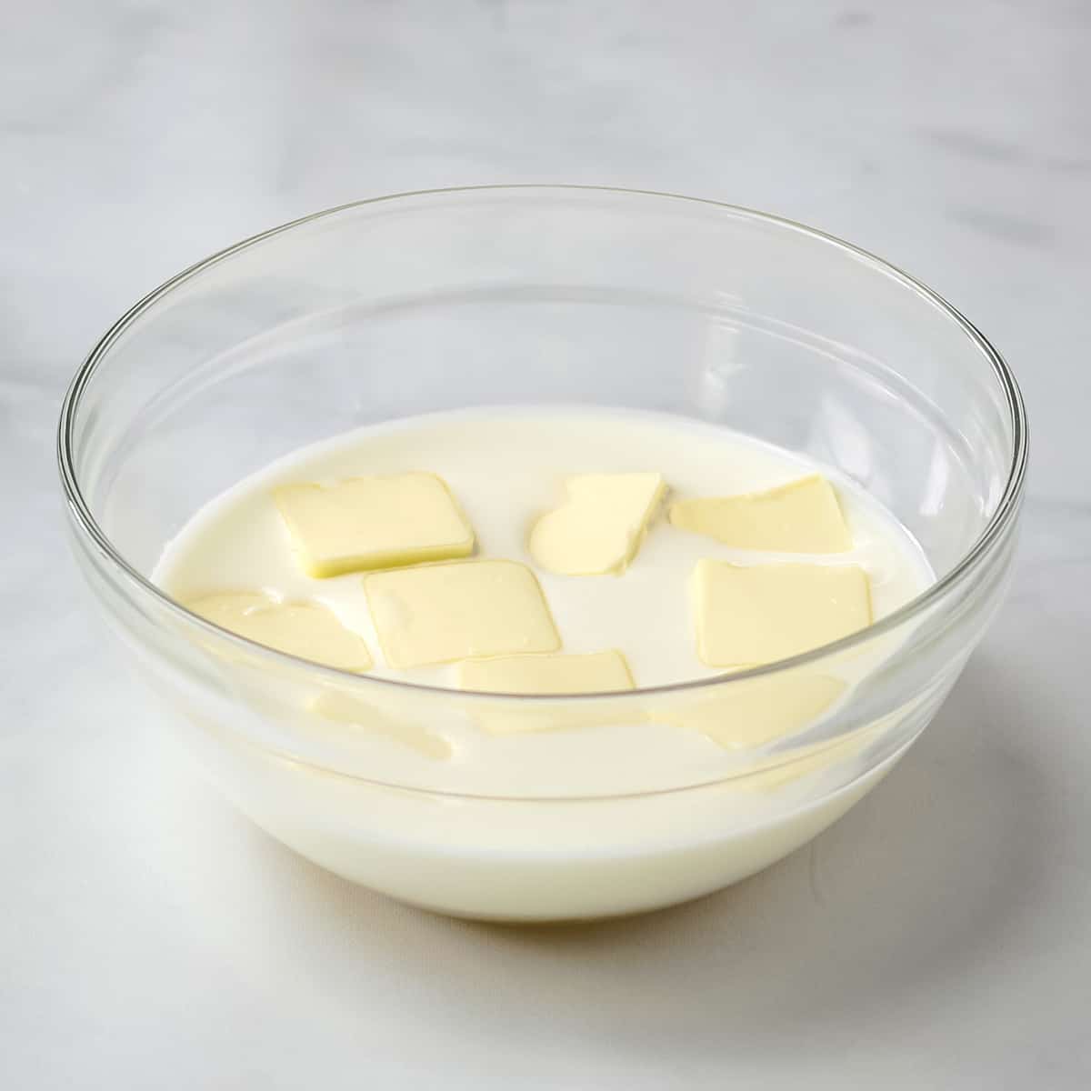 Buttermilk, sugar, and butter pads in a clear glass bowl.