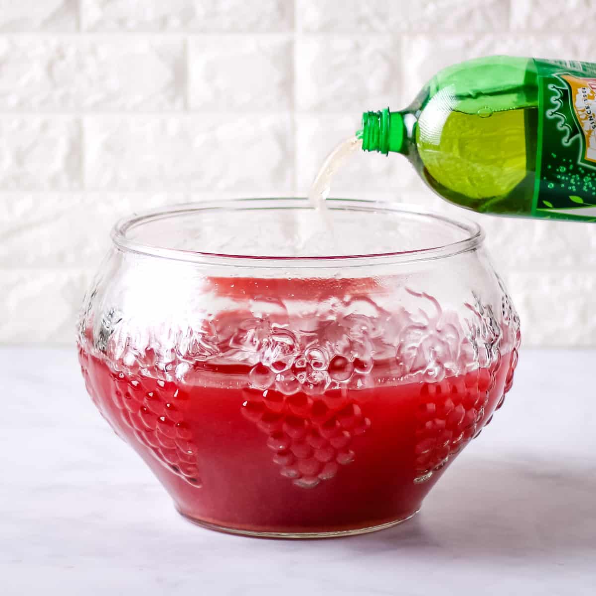 Pouring ginger ale into a large glass punch bowl.