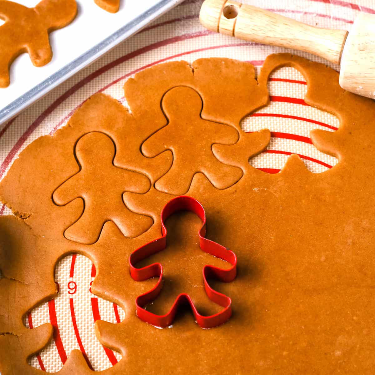Cutting out the cookies with gingerbread man cookie cutters.