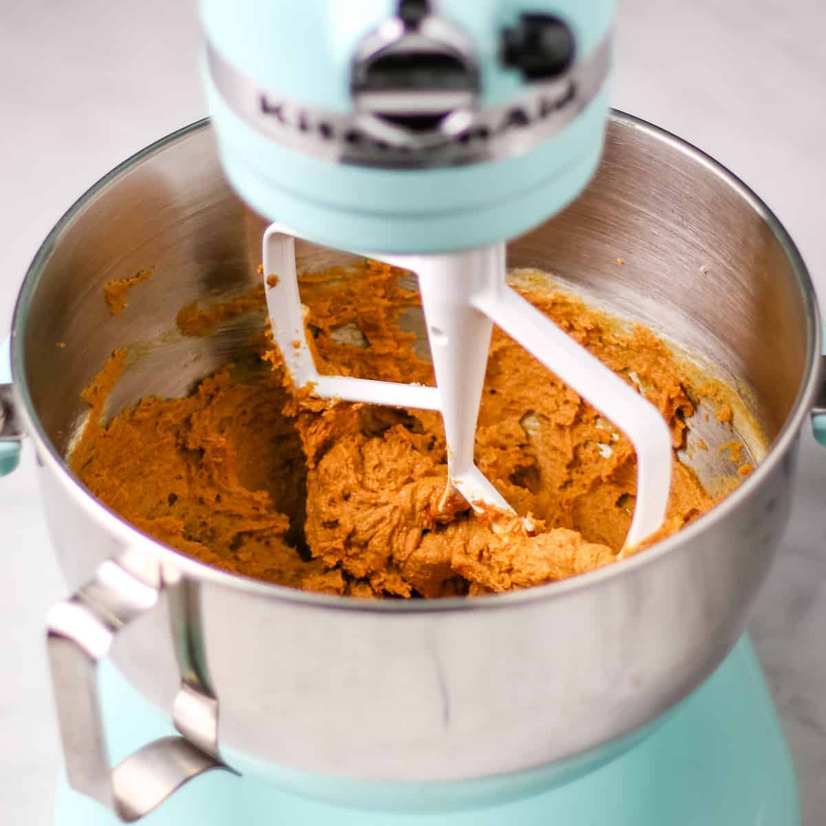Creaming the butter, sugar, and molasses together in a blue electric stand mixer fitted with a paddle attachment.