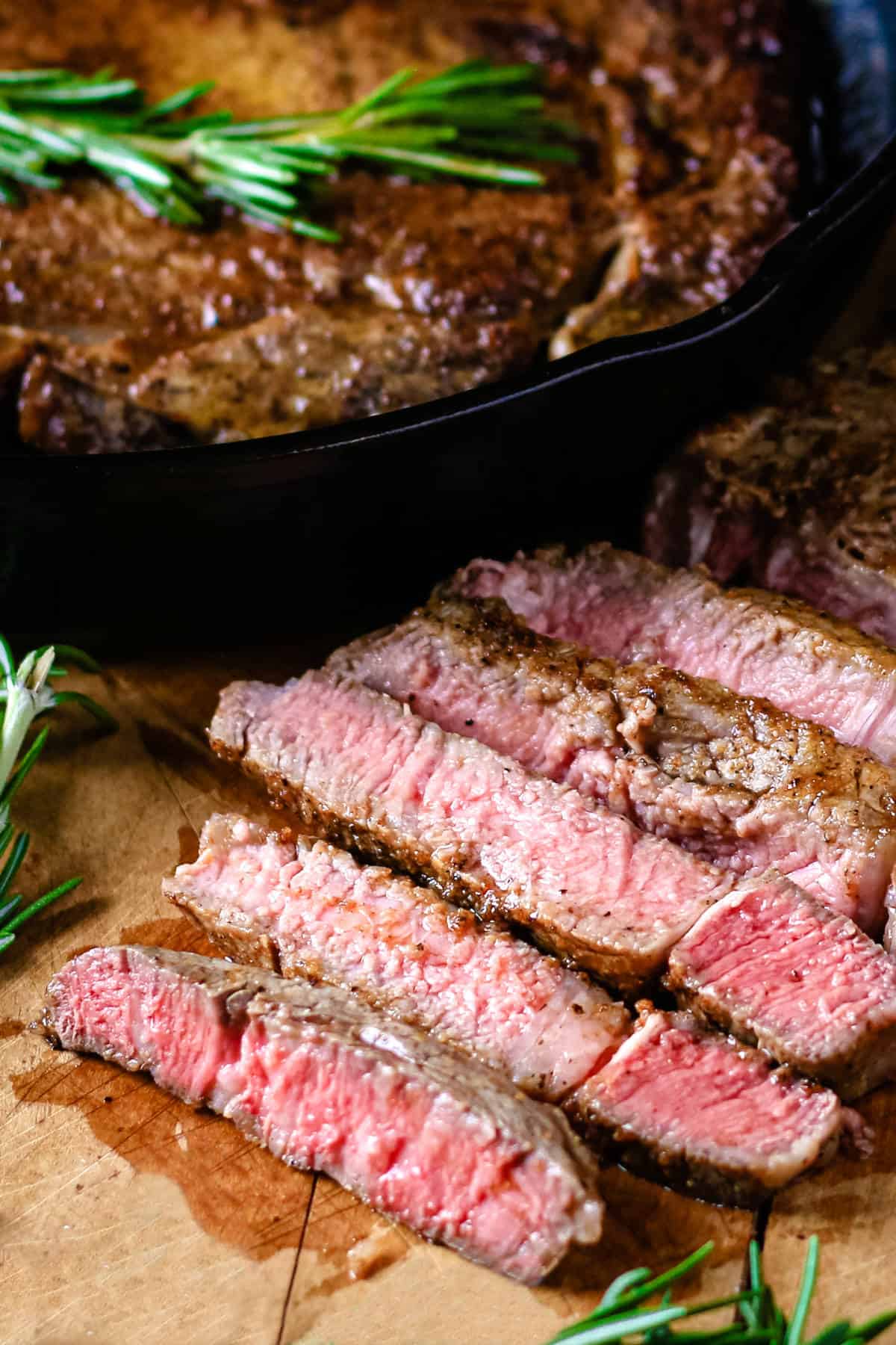 Medium rare steak sliced on a wooden cutting board.