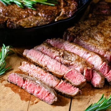 Medium rare steak sliced on a wooden cutting board.