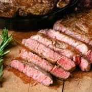 Medium rare steak sliced on a wooden cutting board.