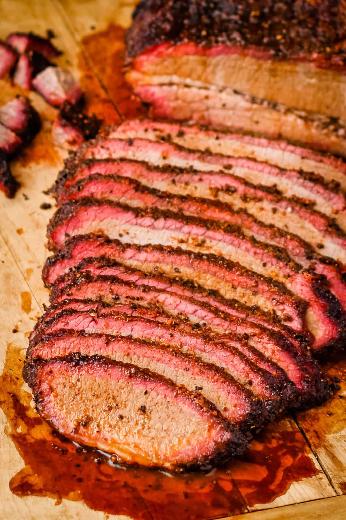 Sliced smoked brisket on a wooden cutting board.