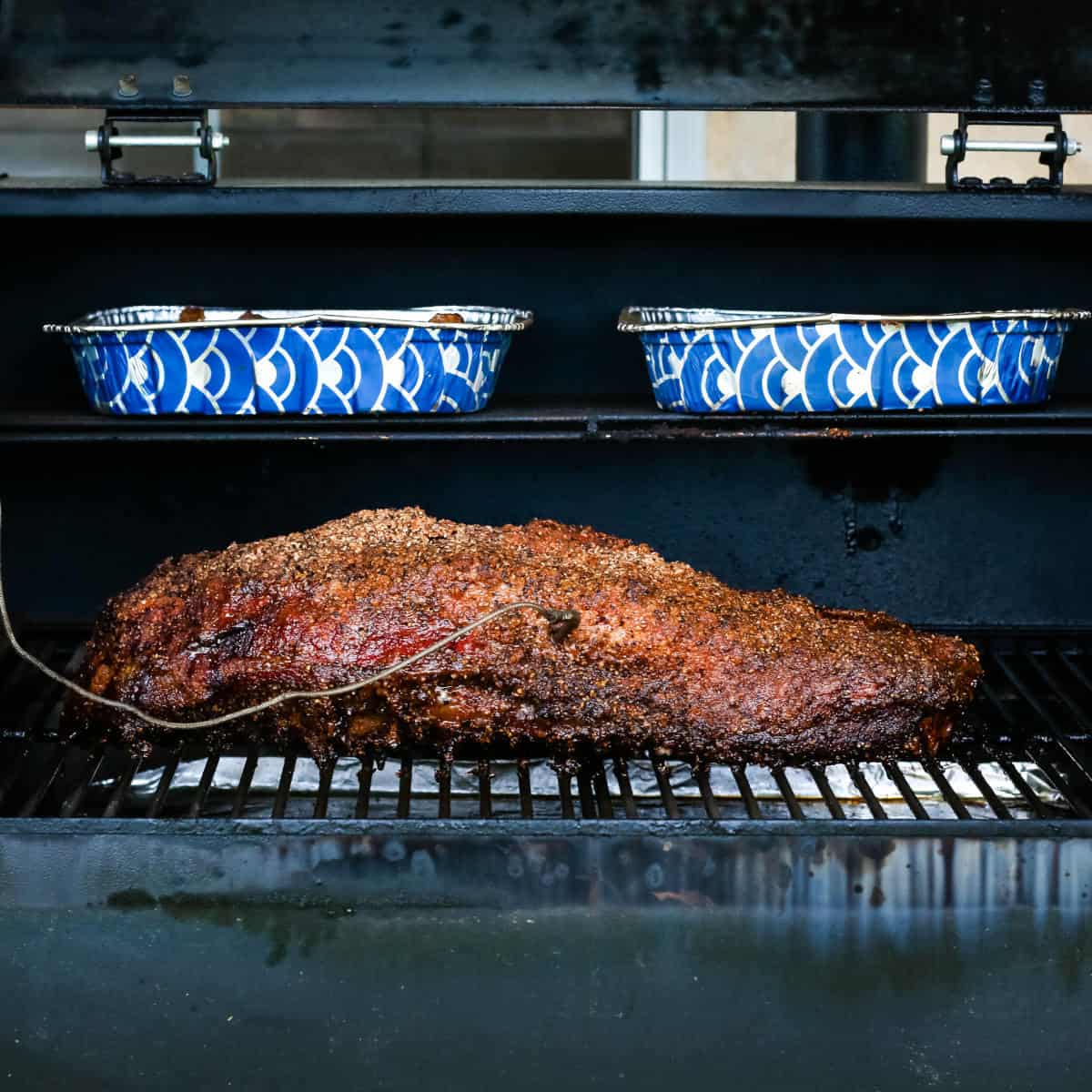 Brisket and the fat trimmings smoking inside a pellet grill.