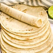Stacked homemade corn tortillas on a white countertop.