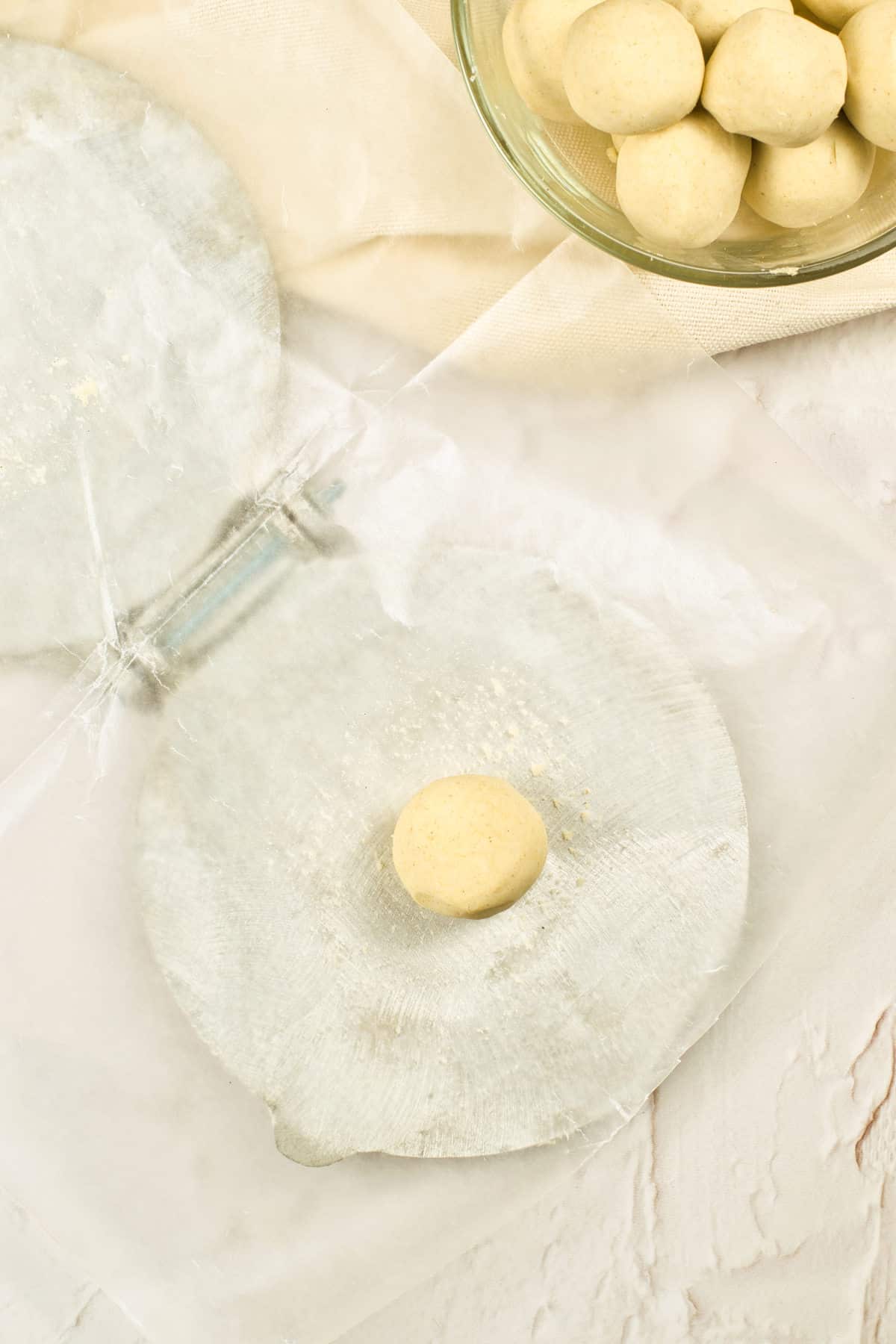 A dough ball on a wax paper lined tortilla press.
